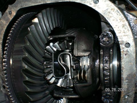 1996 Ford Bronco - Rear axle housing with the differential cover removed, showing the oily ring gear, carrier, spider gears and a limited-slip S-spring clip i…