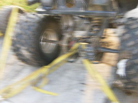 2000 Ford E350 - Close-up view of a vehicle's rear axle and suspension system, secured with yellow tie-down straps. The Supermotors.net logo is visible in t…