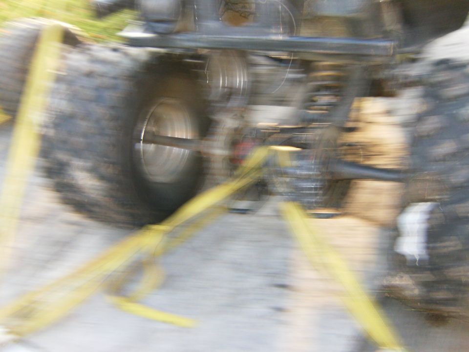 Rear axle and suspension with yellow tie-down straps. Supermotors.net logo visible