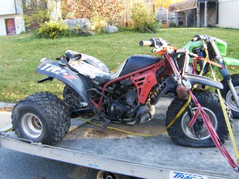 2000 Ford E350 - Three-wheeled ATV and a dirt bike secured with straps on a trailer.