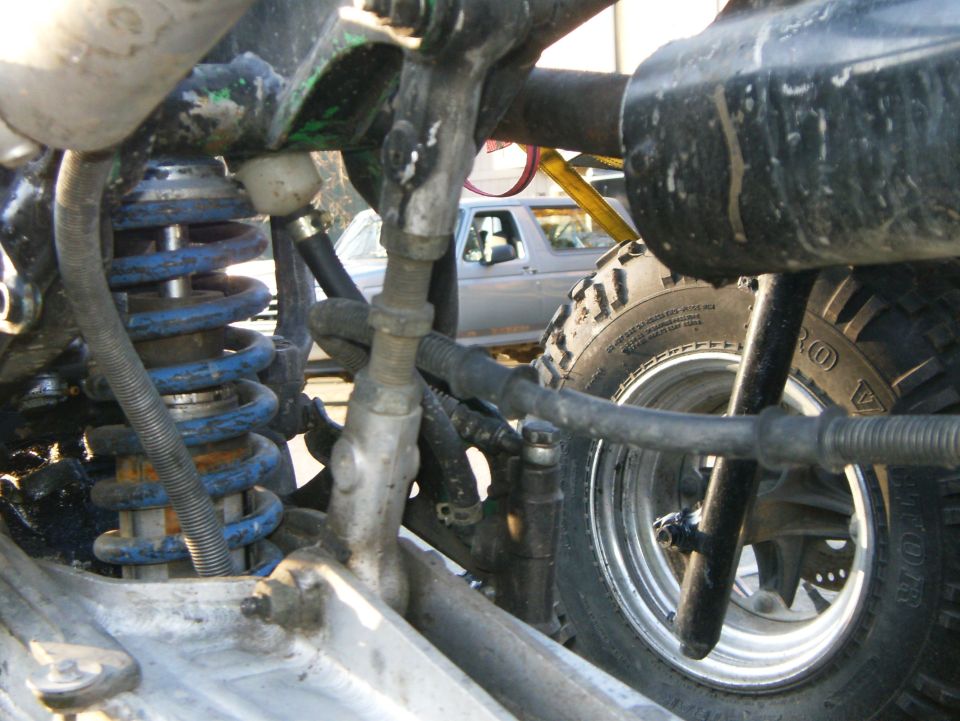 Close-up of suspension and tire, with another vehicle visible in background