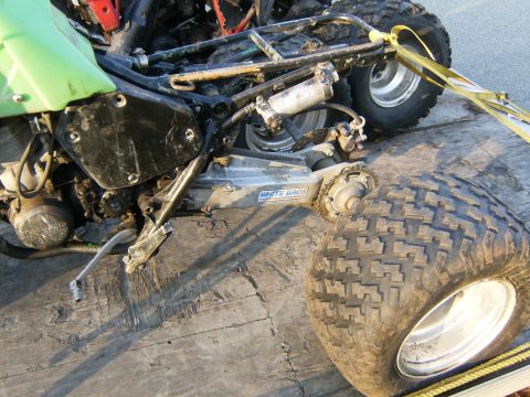 2000 Ford E350 - Close-up of an all-terrain vehicle's frame and suspension system, secured with yellow straps.