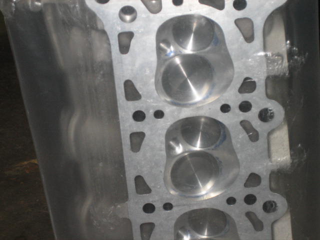 Aluminum engine cylinder head with four visible valve openings, close-up view