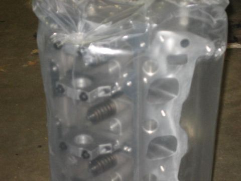 1996 Ford Thunderbird - A close-up view of an engine cylinder head, partially obscured by plastic packaging.