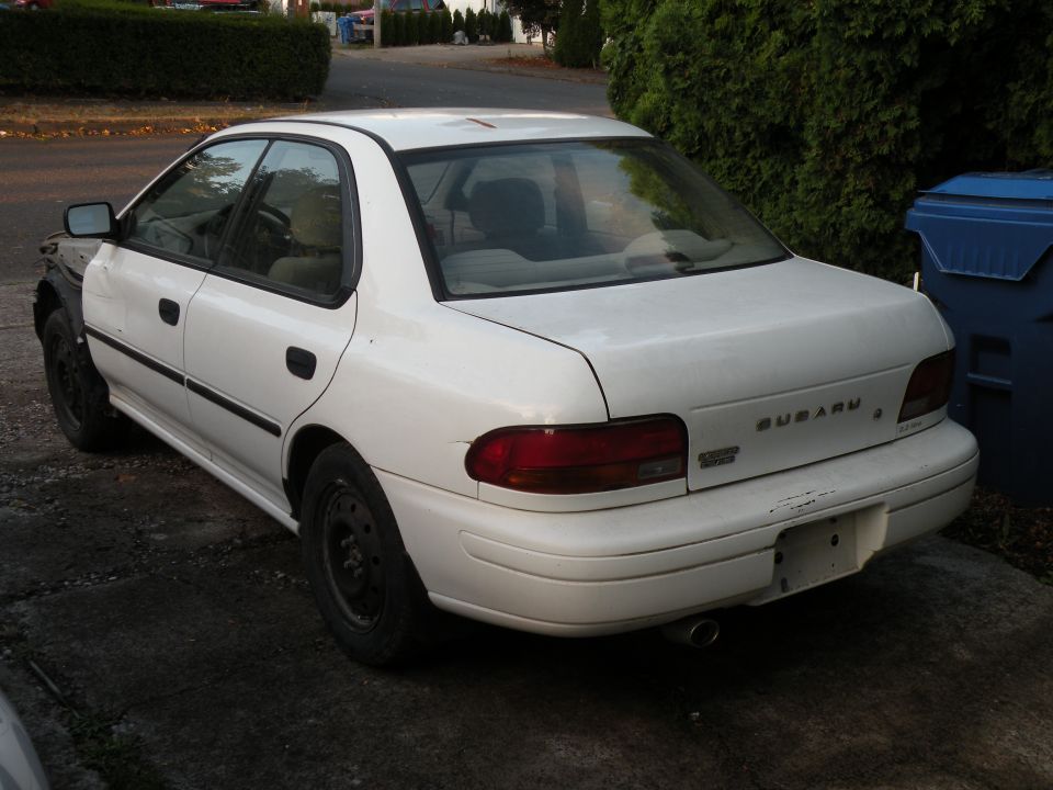 1998 Subaru Legacy sedan, white, missing front left fender, steel wheels