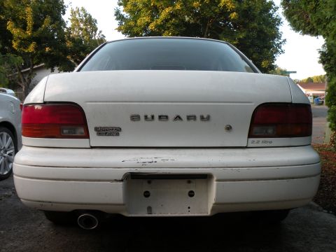 1998 Subaru Legacy - The rear of a white Subaru sedan is shown, its taillights and badging.