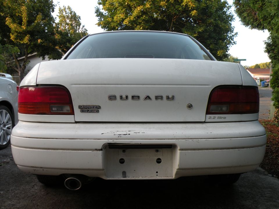 Rear of white Subaru sedan with Impreza 4WD and 2.2 litre badges
