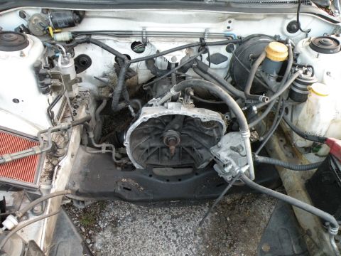 1998 Subaru Legacy - The engine bay of a vehicle is shown with the transmission removed, revealing the engine block and various hoses and wires.