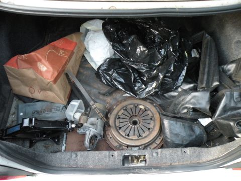 1998 Subaru Legacy - The trunk contains a clutch assembly, starter motor, and a Subaru-branded jack, along with various bags and items.