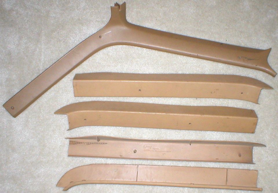 Five tan interior pillar and trim panels laid out on carpet