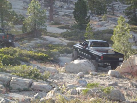 1982 Toyota 4Runner - A black pickup truck navigates a challenging rocky terrain, with another vehicle in the background.