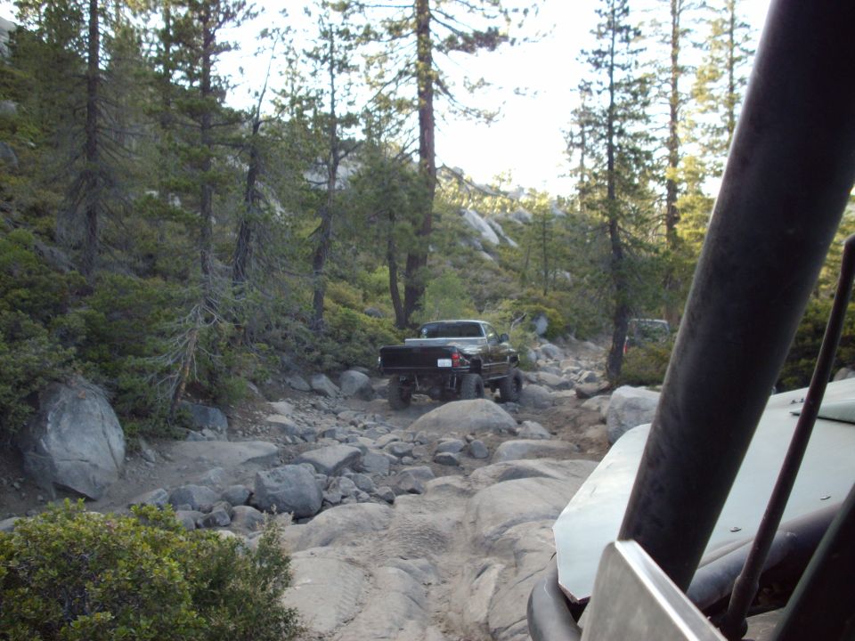 Truck driving on a rocky mountain trail. Another vehicle is in the foreground