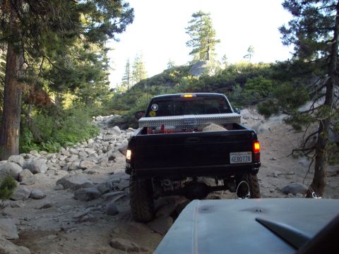 1982 Toyota 4Runner - Pickup truck navigates a challenging rocky trail in a wooded mountain area.