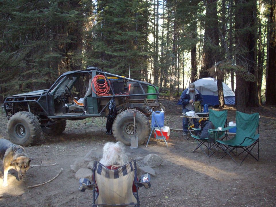Modified off-road buggy parked at a campsite with a tent and chairs set up