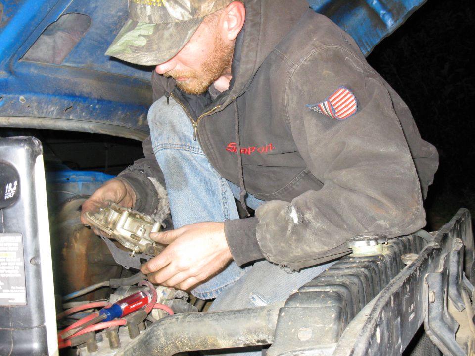 guy working on a carburetor with a screwdriver nearby