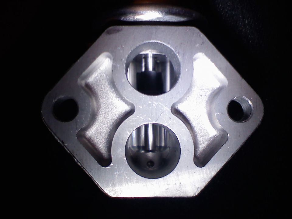 Aluminum flange of an idle air control valve with two ports and two bolt holes on black background