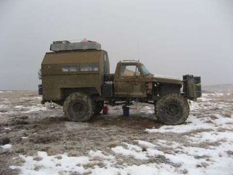 1990 Ford F-250 - This heavily modified pickup truck features a custom camper shell and oversized off-road tires, suggesting it's built for terrain.