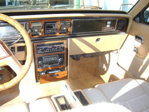 1984 Ford LTD - Interior view of a 1984 Ford LTD showing the tan/beige dashboard with woodgrain trim panels, gauge cluster, stacked radio units, and 'LTD'…