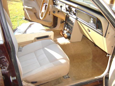 1984 Ford LTD - Passenger-side view of a tan cloth sedan interior with bucket seats, woodgrain dash trim and column shifter.