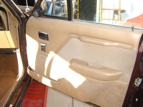 1984 Ford LTD - Interior view of a car door panel, showing tan upholstery and chrome accents.