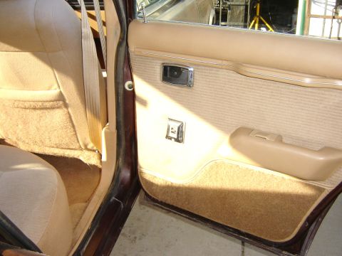 1984 Ford LTD - Interior view of a car's door panel and seat, showing tan and beige upholstery.