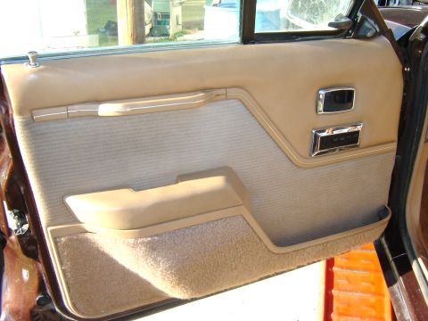1984 Ford LTD - Interior door panel of a car, showing tan upholstery and chrome accents, with a visible Supermotors.net watermark.