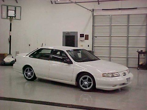 1993 Ford Taurus - White 1993 Ford Taurus sedan is parked inside a garage with a large overhead door.