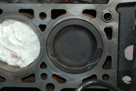 2007 Ford Mustang - Close-up view of an engine block's cylinder bores, one containing a piston and the other temporarily plugged with paper.