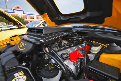 2007 Ford Mustang - The engine bay of a yellow car is shown with the hood open, revealing the V8 engine and various components.