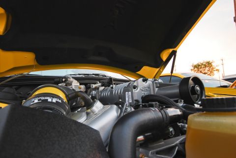 2007 Ford Mustang - Close-up of a yellow car's engine bay, a prominent supercharger and air intake system.