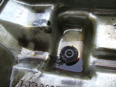 1996 Ford F-250 - Close-up of a transmission pan interior revealing dark fluid, debris, and a filter element.