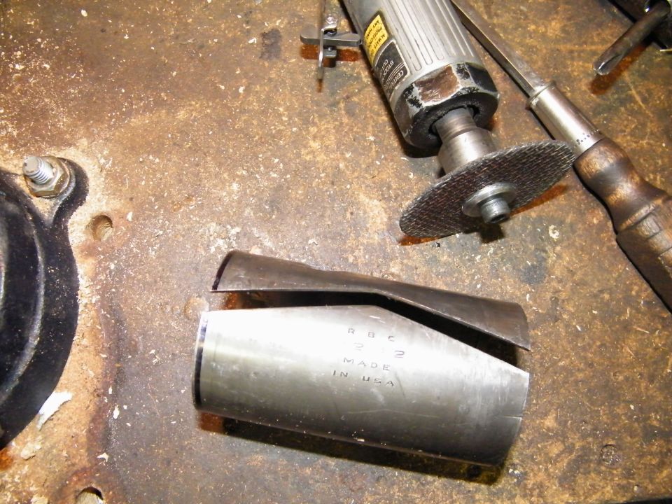 Metal bushing stamped 'RBC MADE IN USA' on workbench with die grinder and tools