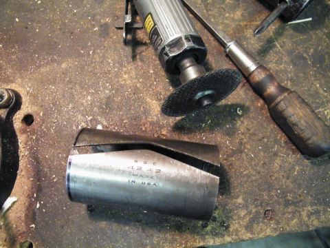 1912 Ford Model T - A metal part with text is on a workbench next to tools, suggesting a repair or fabrication process.