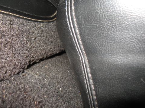 1968 Shelby GT500 - Close-up of a car's interior console and carpet, showing textured surfaces and stitching details.