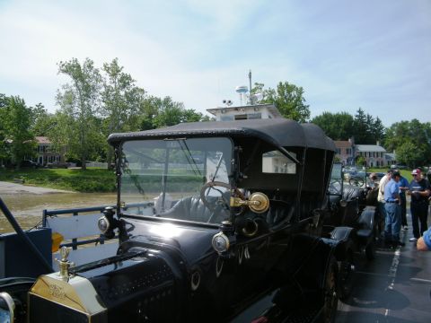 1915 Ford Model T - A black 1915 Ford Model T touring car is seen on a ferry, with other vehicles and people visible in the background.