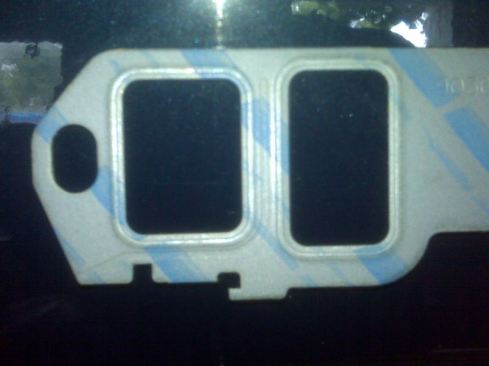 close-up of an engine gasket with two large rectangular openings and blue stripes