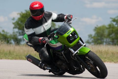2001 Kawasaki KZ1000-A1 - A rider in full gear takes a corner on a green motorcycle, with "SUPERMOTORS.NET" visible at the bottom.