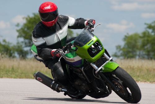 Rider leans into a turn on a green motorcycle with a red helmet