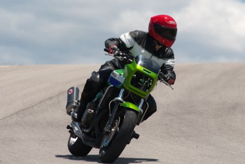 2001 Kawasaki KZ1000-A1 - A rider leans into a turn on a green motorcycle under a cloudy sky.