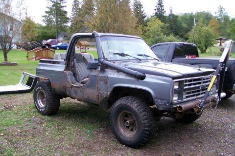 1988 Chevrolet Blazer - This heavily modified pickup truck features a snorkel and is parked next to another vehicle in a yard.