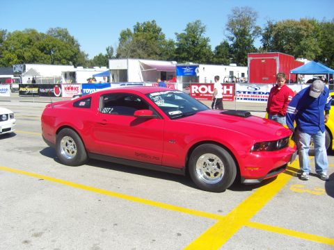 2007 Ford Mustang - A red Ford Mustang is parked at a drag strip with people standing nearby.