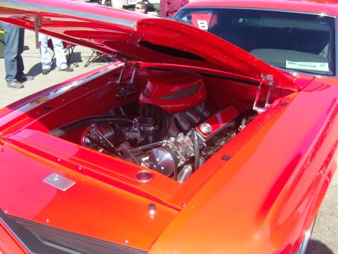 2007 Ford Mustang - The engine bay of a red car is open, revealing a powerful V8 engine with custom modifications.