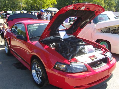 2007 Ford Mustang - A red Ford Mustang is displayed with its hood open, revealing the engine compartment. Another vehicle is visible to the right.