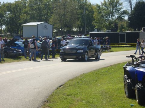 2007 Ford Mustang - Black Ford F-150 SVT Lightning pickup truck at an outdoor event with other vehicles present.