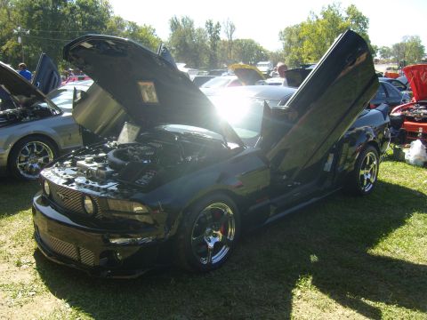 2007 Ford Mustang - Customized 2007 Ford Mustang with gullwing doors and hood open at a car show.
