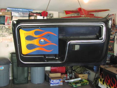 1981 Ford Bronco - A black door panel with flame graphics is suspended in a garage.