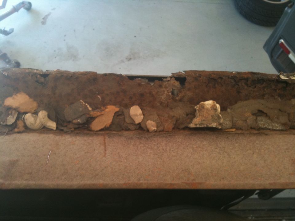 Severely rusted metal panel with corrosion and debris on a workbench