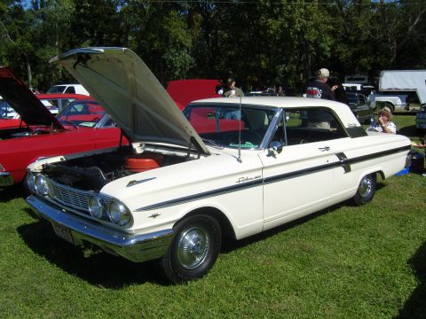 2007 Ford Mustang - A white 1962 Ford Fairlane 500 coupe is displayed with its hood open at an outdoor car show.