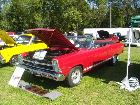 2007 Ford Mustang - A red 1967 Ford Fairlane convertible is displayed with its hood open at a car show, alongside a yellow car.