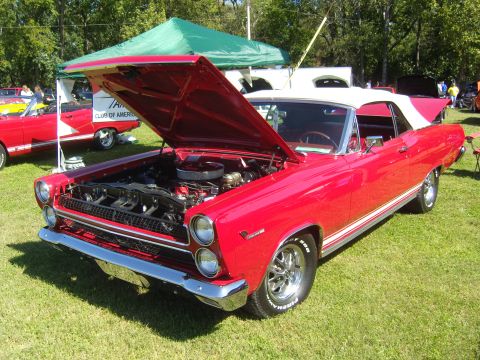 2007 Ford Mustang - Classic red Mercury Cougar convertible displayed with its engine visible at an outdoor car show.